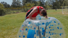 a man in a red and black jersey is playing in a bubble ball with the word com on the side