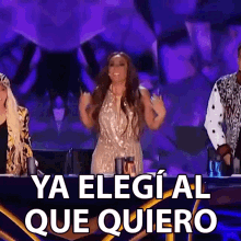 a woman in a sequined dress stands in front of a sign that says ya elegi al que quiero on it