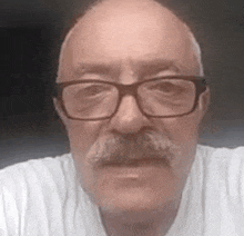 a man with glasses and a mustache is wearing a white shirt .