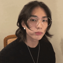 a young man with long hair wearing glasses and a black shirt