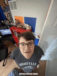 a man wearing a whistler t-shirt is standing in a room