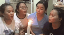 a group of young girls are blowing out a candle .