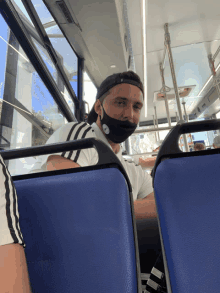 a man wearing a black face mask is sitting on a bus