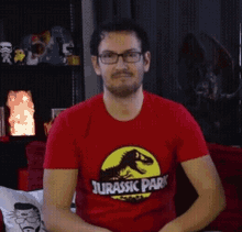 a man wearing a red jurassic park shirt