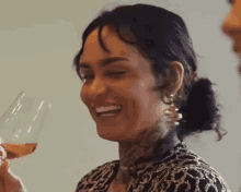 a woman is smiling while drinking a glass of wine .