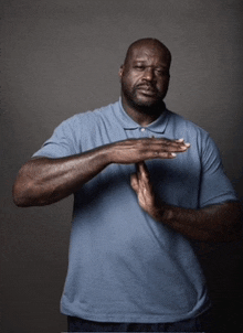 a man wearing a blue shirt is making a gesture with his hands