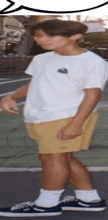 a boy wearing a white shirt and yellow shorts is standing on a tennis court