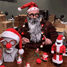 a man with a beard wearing a santa hat and glasses is sitting at a table with christmas decorations .