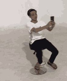 a young man is sitting on a chair taking a picture of himself