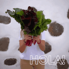 a woman is holding a bunch of lettuce in front of her face and the word hola is written below her