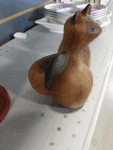 a wooden cat with blue eyes is sitting on a table