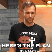 a man wearing a black shirt that says look mom here 's the plan