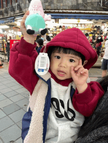 a little girl holding a stuffed animal wearing a jacket with the number 86 on it