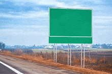 a green highway sign is sitting on the side of a road .