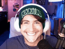 a man wearing headphones and a celtics beanie smiles for the camera