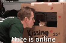 a man kissing a cat in a cardboard box that says kissing 25 cents