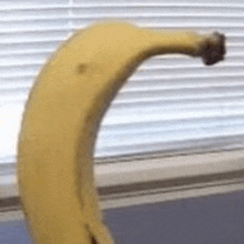 a banana is sitting on a counter next to a window with blinds .