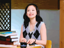 a woman sitting at a desk with a stack of books and the word pulled out on the bottom left