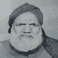 a man with a beard wearing a turban looks at the camera in a black and white photo