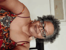 a woman wearing glasses and a floral top smiles