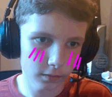 a young boy wearing headphones and a microphone has pink lines on his face