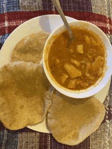 a bowl of soup sits on a plate with tortilla chips