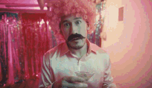 a man with a pink afro and mustache is holding a martini glass .