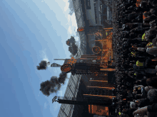 a large crowd of people watching a concert with smoke coming out of the roof