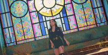 a woman is standing in front of a stained glass window in a church .