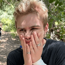 a young man is covering his face with his hands .