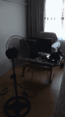 a desk with a computer monitor and a fan on it