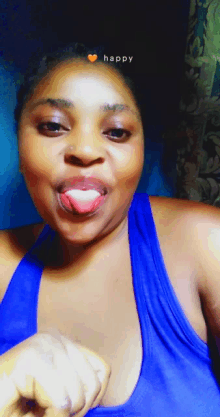 a woman in a blue tank top is sticking her tongue out with the word happy above her