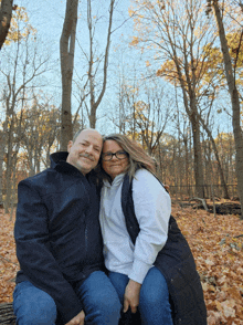 a man and a woman are posing for a photo in the woods