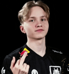 a young man wearing a black shirt with red bull on the sleeves giving the middle finger