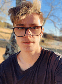 a young man wearing glasses and a black shirt is looking at the camera