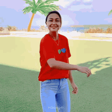 a woman in a red shirt and blue jeans is smiling