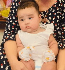 a woman in a polka dot dress is holding a baby in her arms and the baby is wearing a diaper