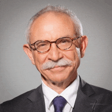 a man with glasses and a mustache is wearing a suit