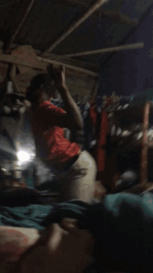 a man in a red shirt is dancing in a room