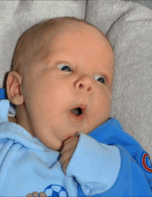 a baby is wearing a blue sweater with a soccer ball on it