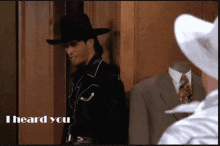 a man in a cowboy hat is standing next to a mannequin with the words " i heard you " written on it