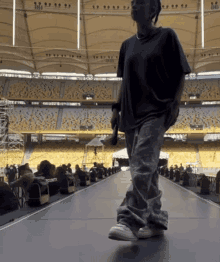 a person walking on a stage in front of a stadium