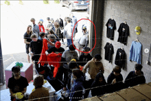 a group of people standing in front of a brick wall with shirts on it