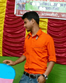 a man in an orange shirt is standing in front of a sign that says 82