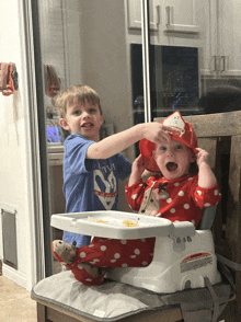 a baby wearing a santa hat is sitting on a high chair next to a boy