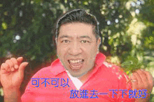 a man in a red shirt is making a funny face with chinese writing behind him .