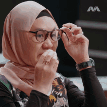 a woman wearing a hijab and glasses has a ring on her finger