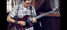 a young man is playing a guitar in front of a microphone .