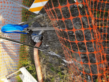 a hose is attached to an orange fence along the side of the road