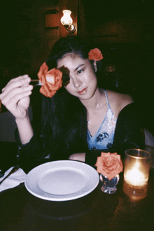 a woman is sitting at a table with a plate and a candle in front of her